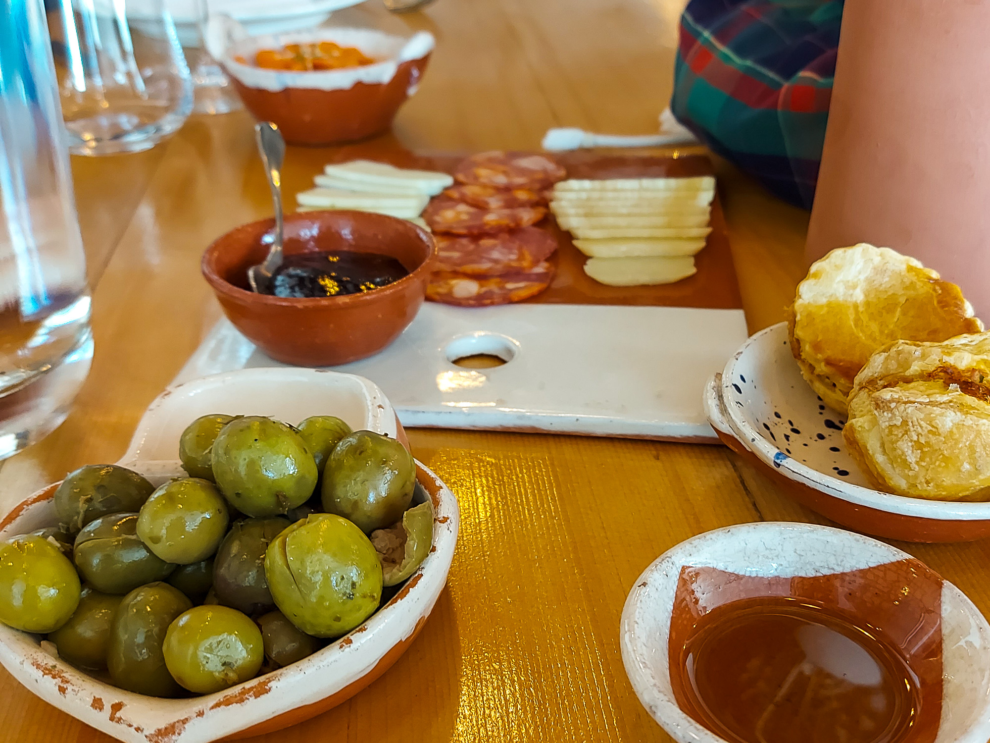 Portugiesische Jause aus Oliven, Olivenöl, Brot, Wurst, Käse und Karottensalat zur Weinverkostung