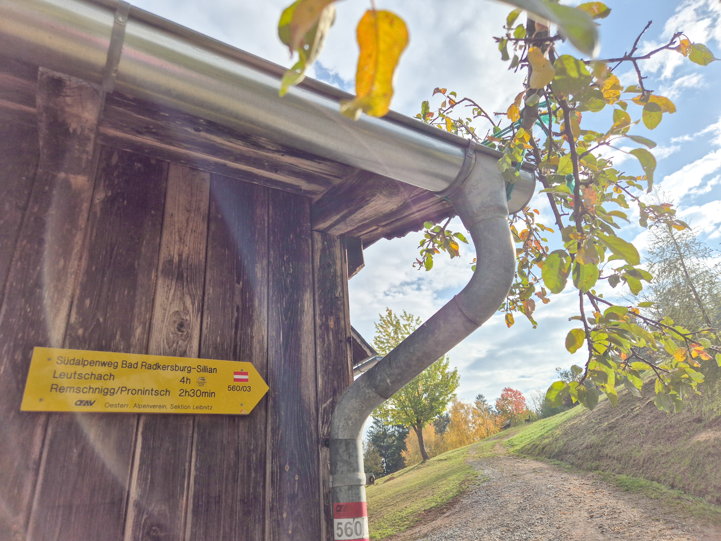 Wandern am Grenzpanoramaweg Auf einer Holzhütte ist ein gelber Wanderwegweise angebracht